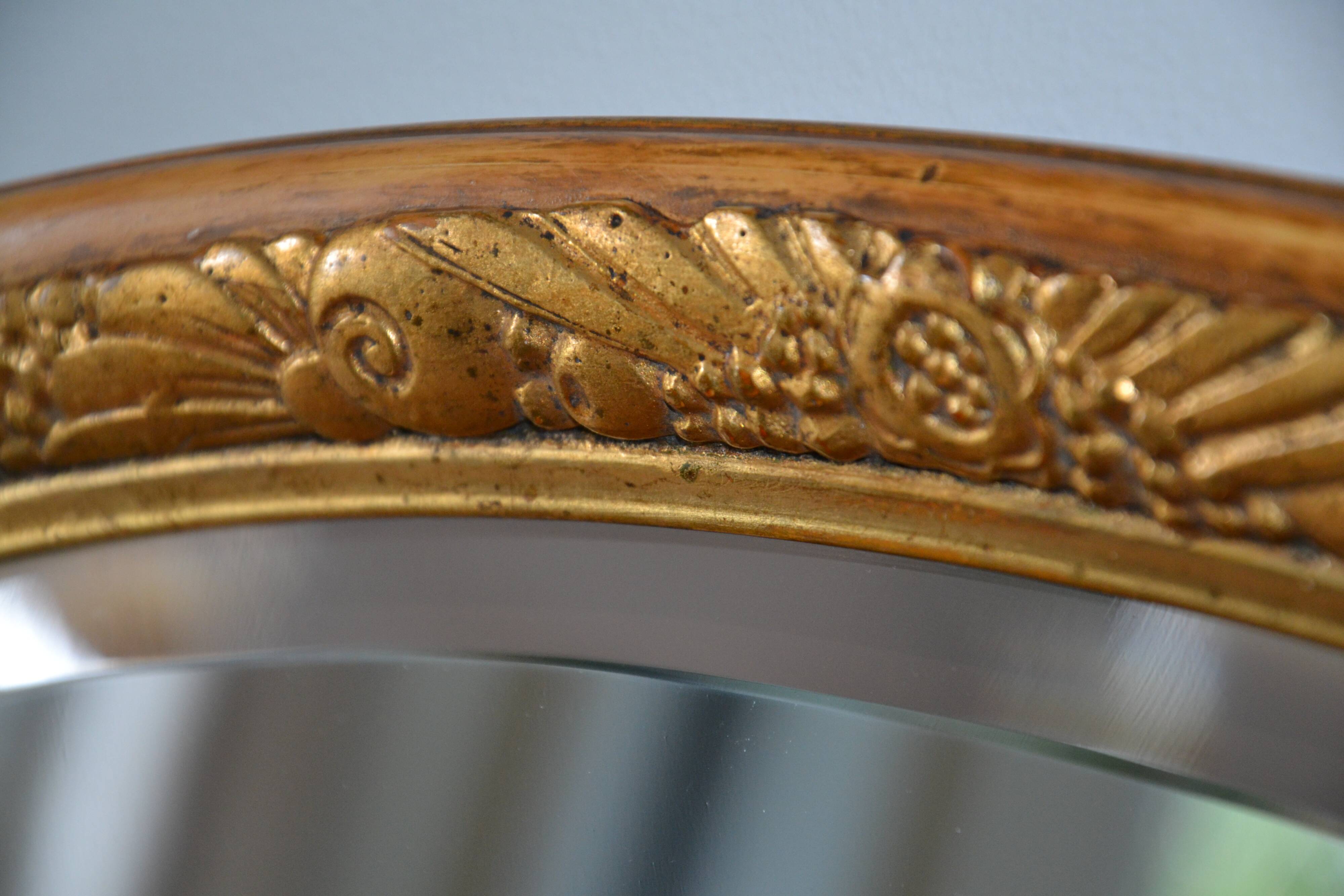 Old oval beveled wooden mirror, partly gilded and carved