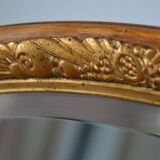Old oval beveled wooden mirror, partly gilded and carved