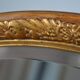 Old oval beveled wooden mirror, partly gilded and carved
