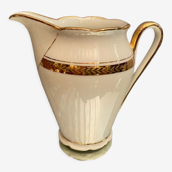 Porcelain milk jug with gold decoration on a white background