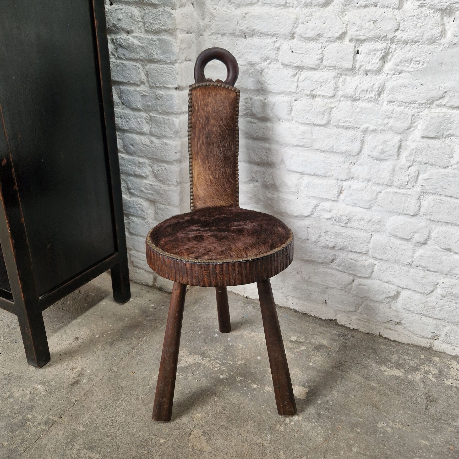 Antique tripod chair in solid wood and animal skin.