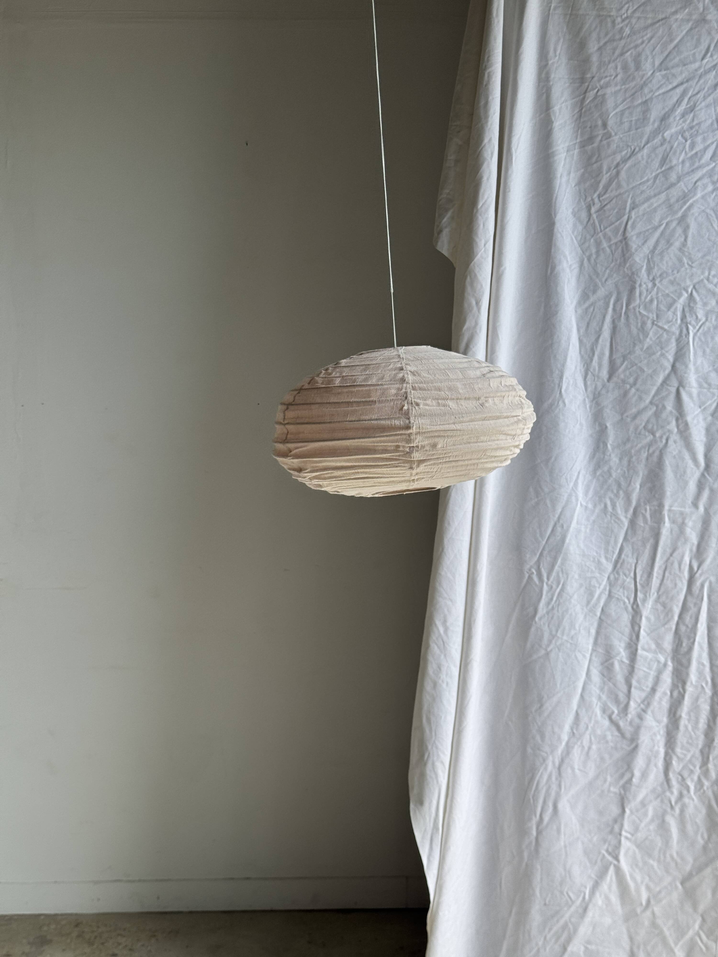 Average suspension in natural rattan and linen, Japanese-style, flattened oval in pink.