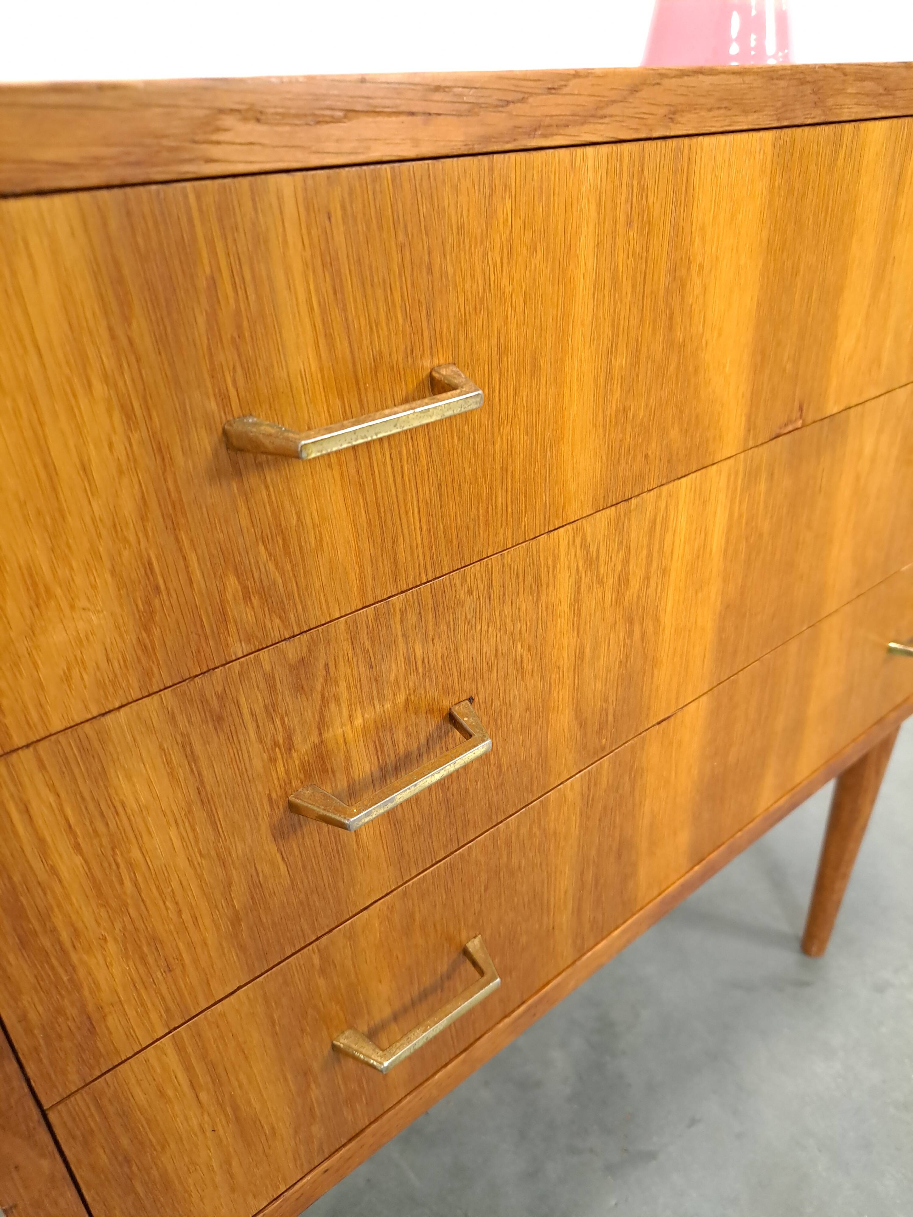 Commode danoise avec de hauts pieds et des poignées dorées.