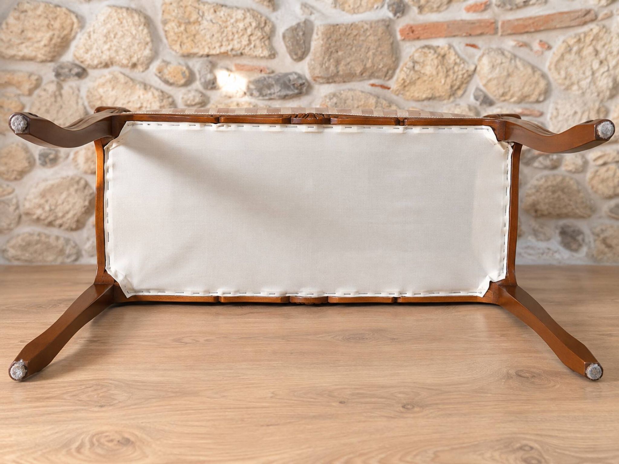 Two-seater bench in carved wood, with curved armrests.