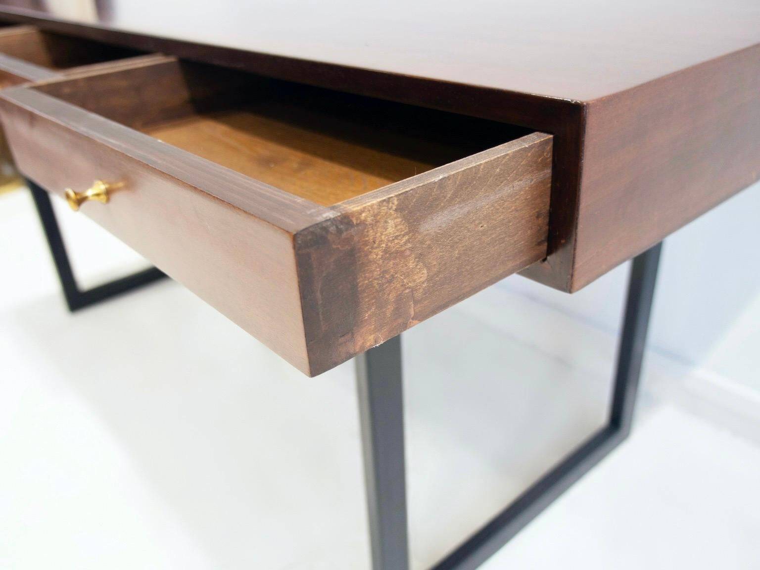Wooden desk with drawers and black lacquered legs.