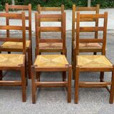 6 light solid wood chairs with high straw backs, farmhouse style.