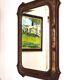 Italian sculpted mirror, patinated brown and gold wood, architectural frame from the 1960s.
