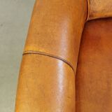 Comfortable, cozy armchair made of sheepskin leather with a neat finish and decorative nailhead trim
