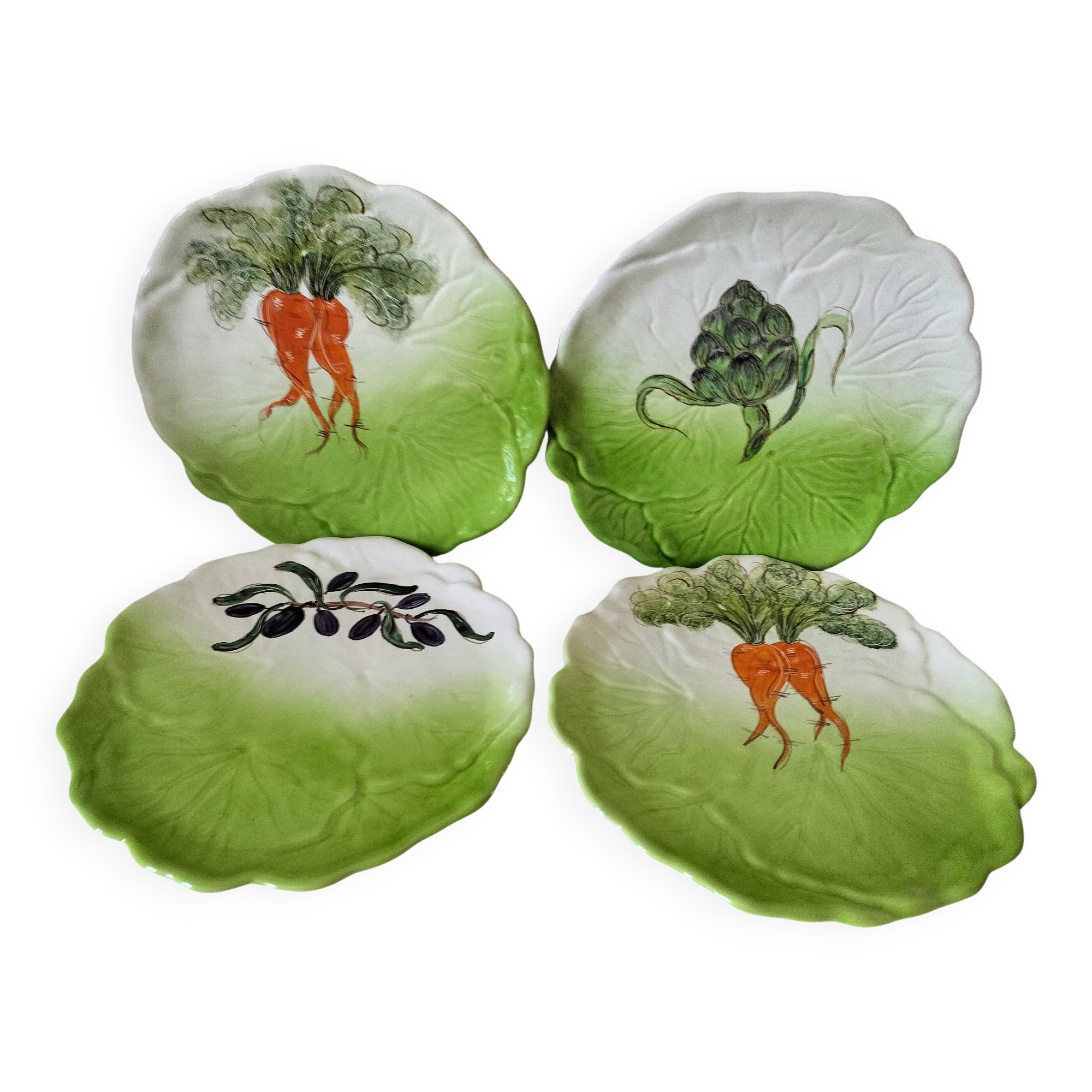 4 hand-decorated earthenware plates with vegetable and green leaf designs.