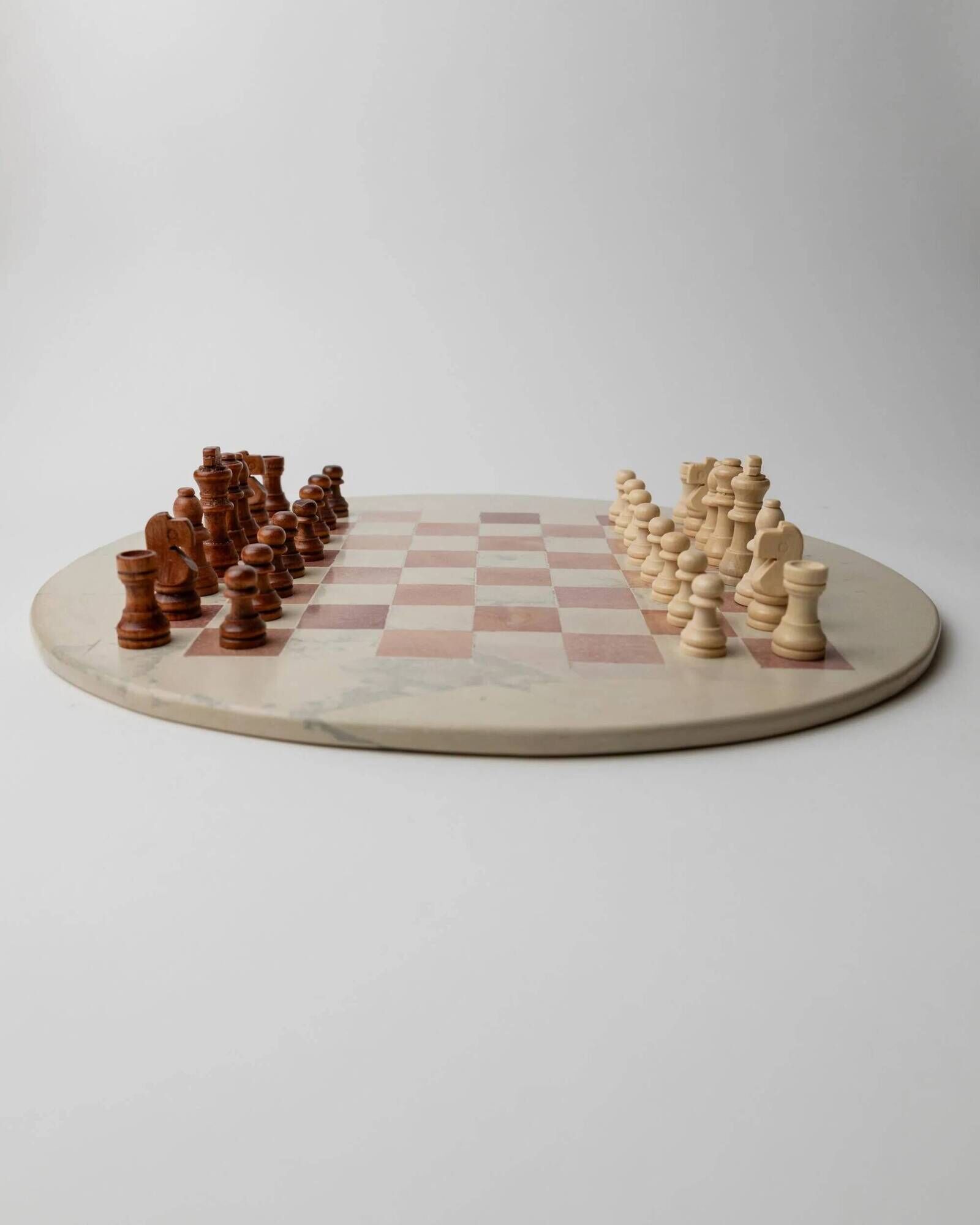Vintage 1980s round chess set in marble, with a beige and pink marble board and wooden pieces.