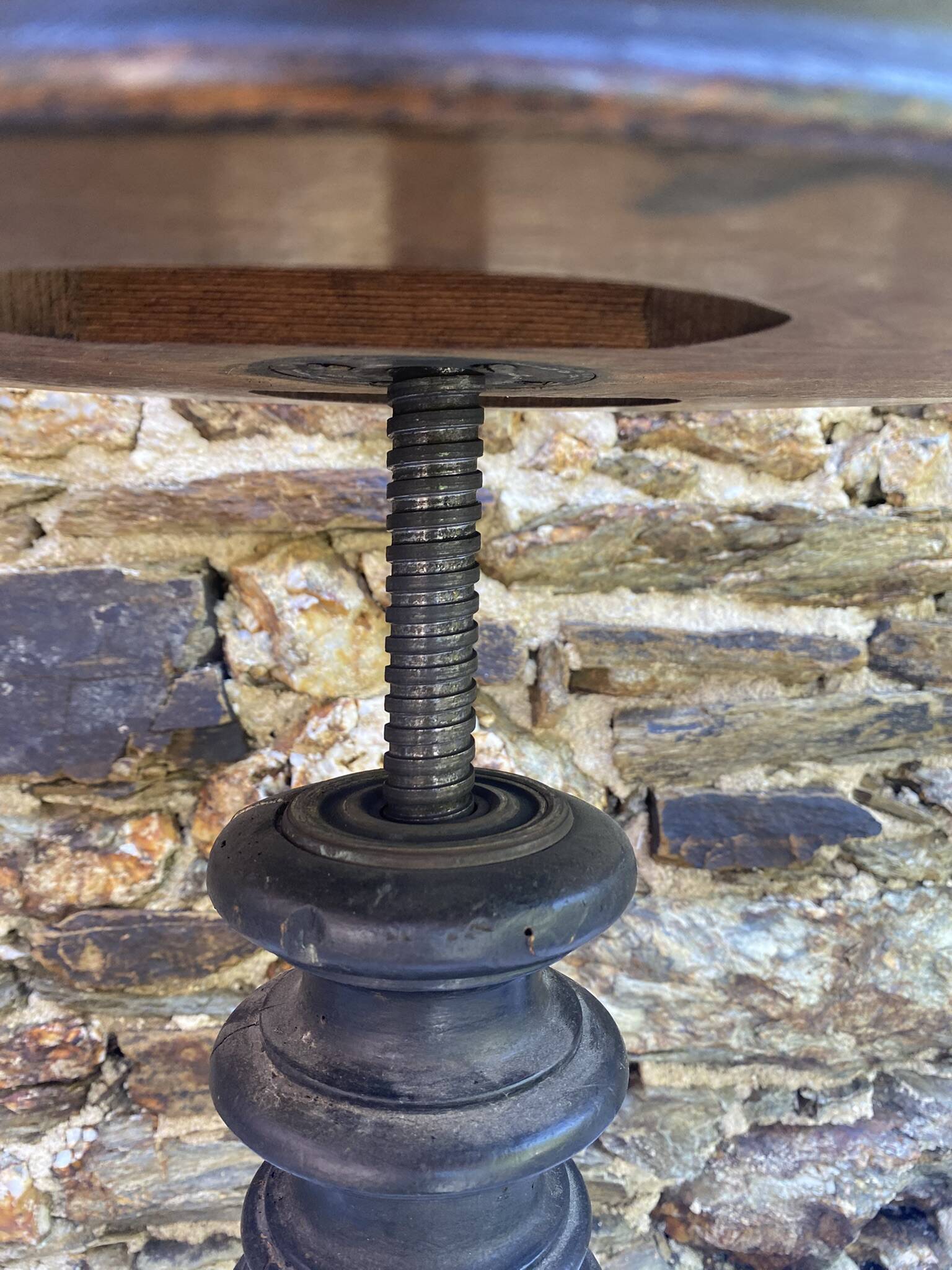 Old adjustable piano stool, blackened wood, metal screws, embroidered seat.