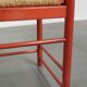 Red vintage wooden chair from the 1970s with a woven wicker seat