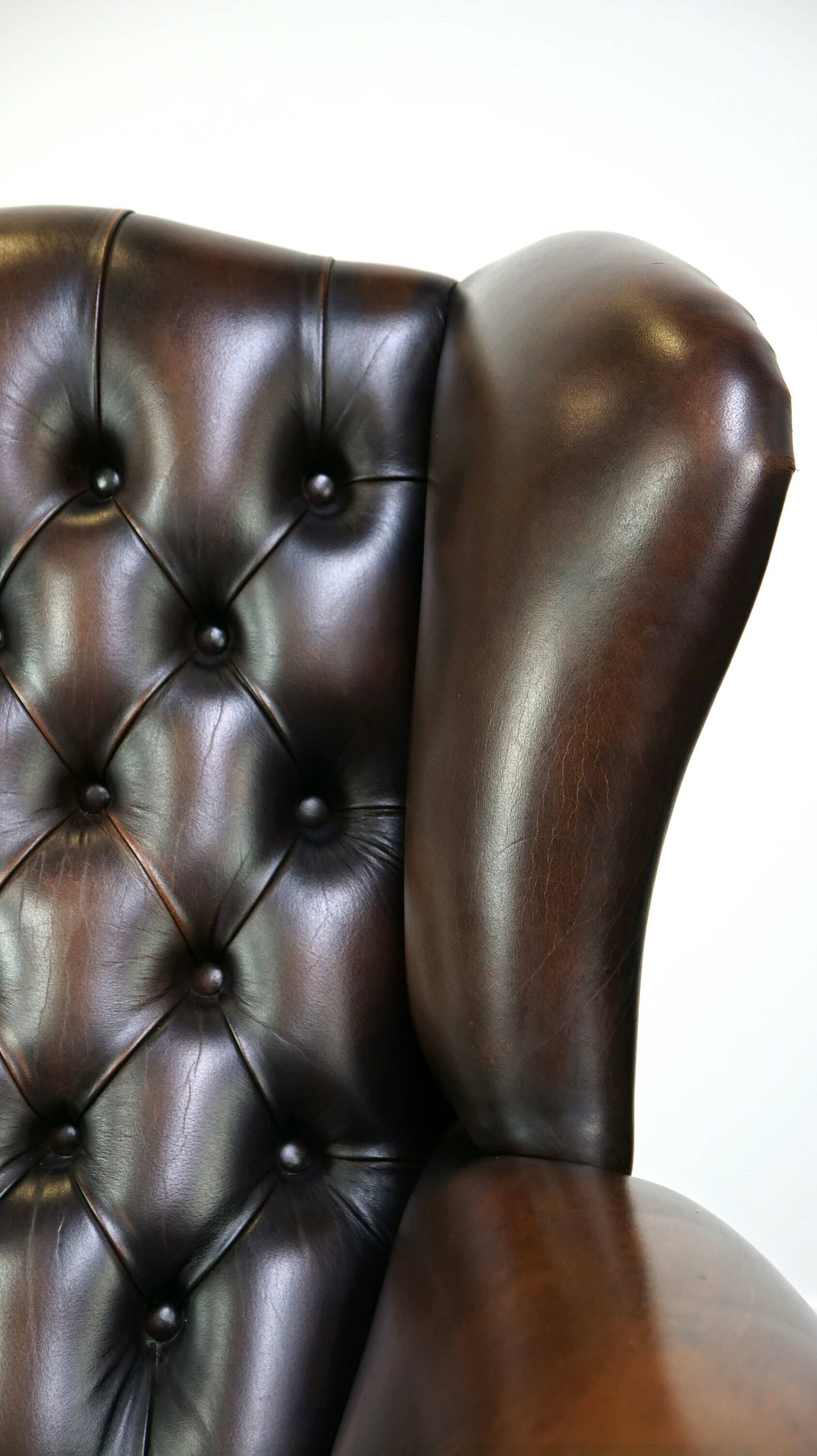 Chesterfield wing chair in dark brown leather with a luxurious appearance