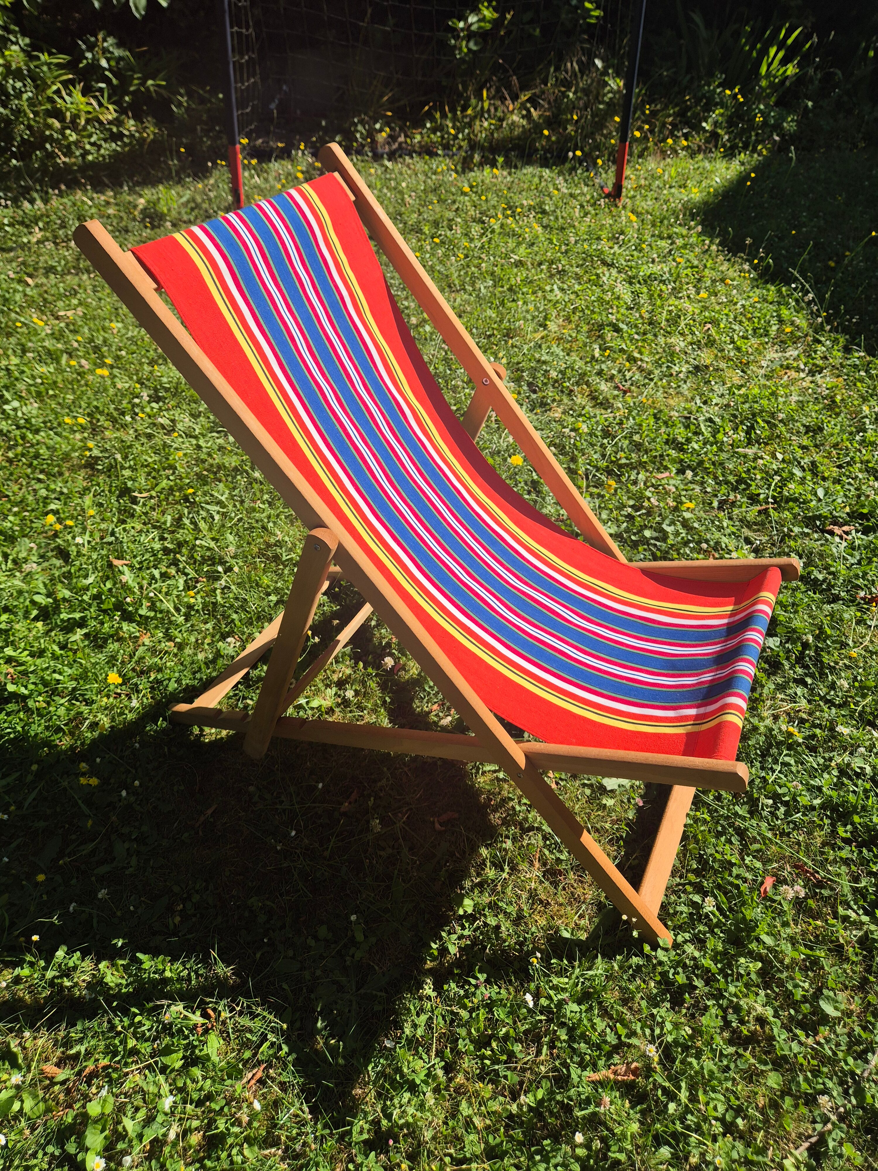 vintage wooden deck chair with red, blue, and yellow striped fabric