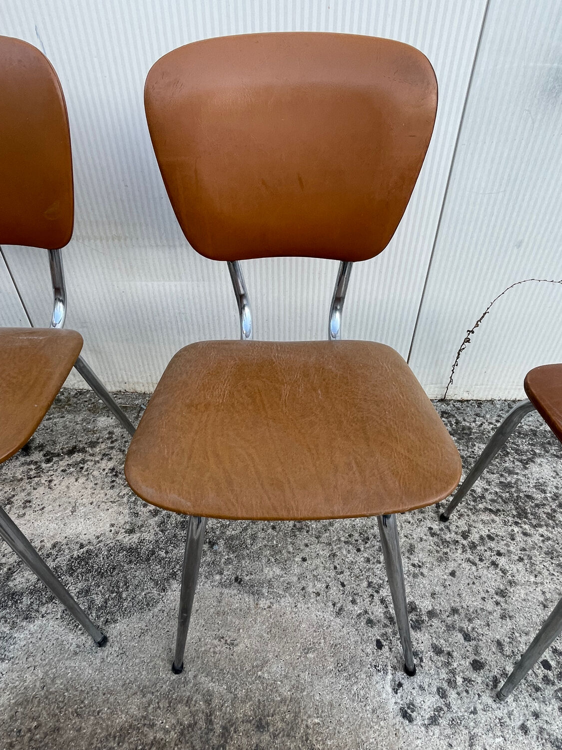 3 chairs and a vintage stool in faux leather and tubular design.