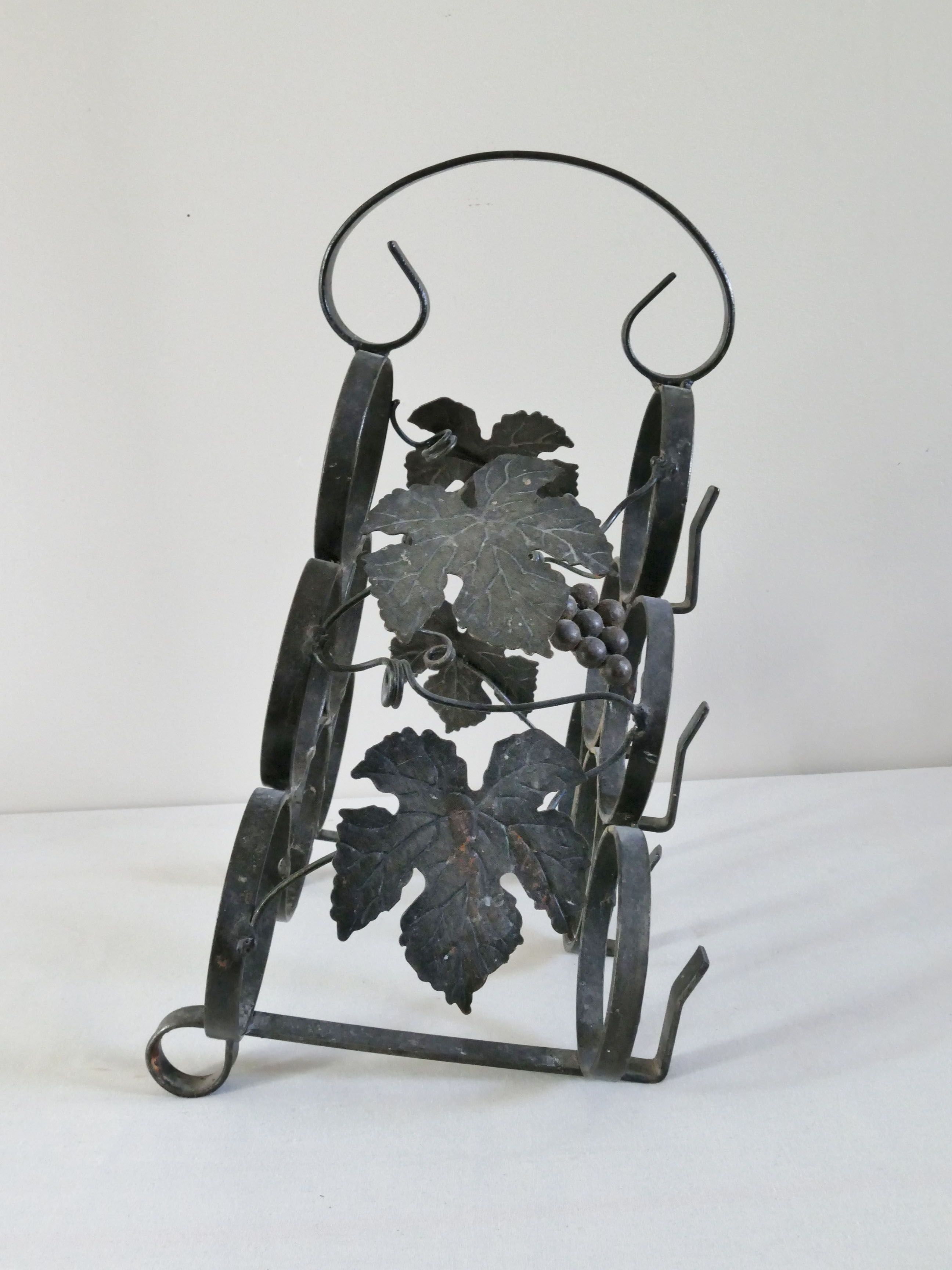 Vintage black wrought iron bottle holder decorated with vine leaves