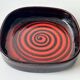 Large decorative ceramic catchall with red and black spiral pattern.