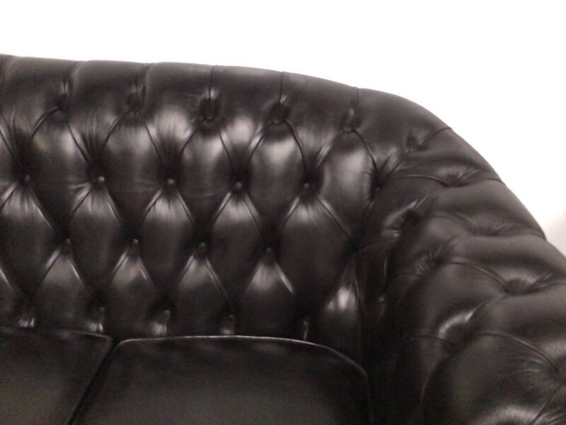 Three-seater black leather chesterfield sofa
