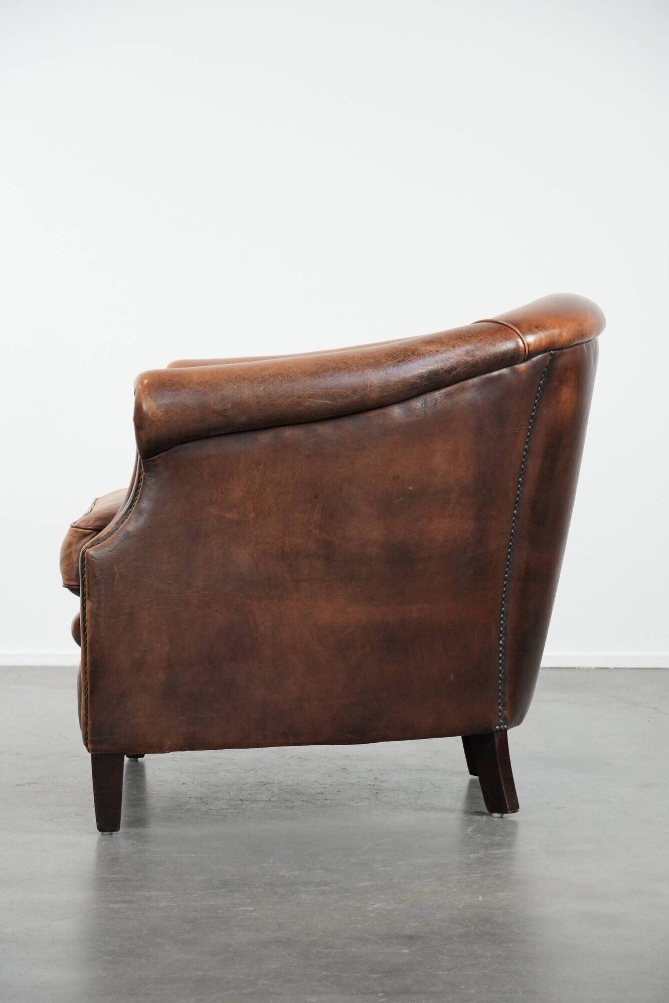 Club chair made of sheepskin leather finished with decorative nails