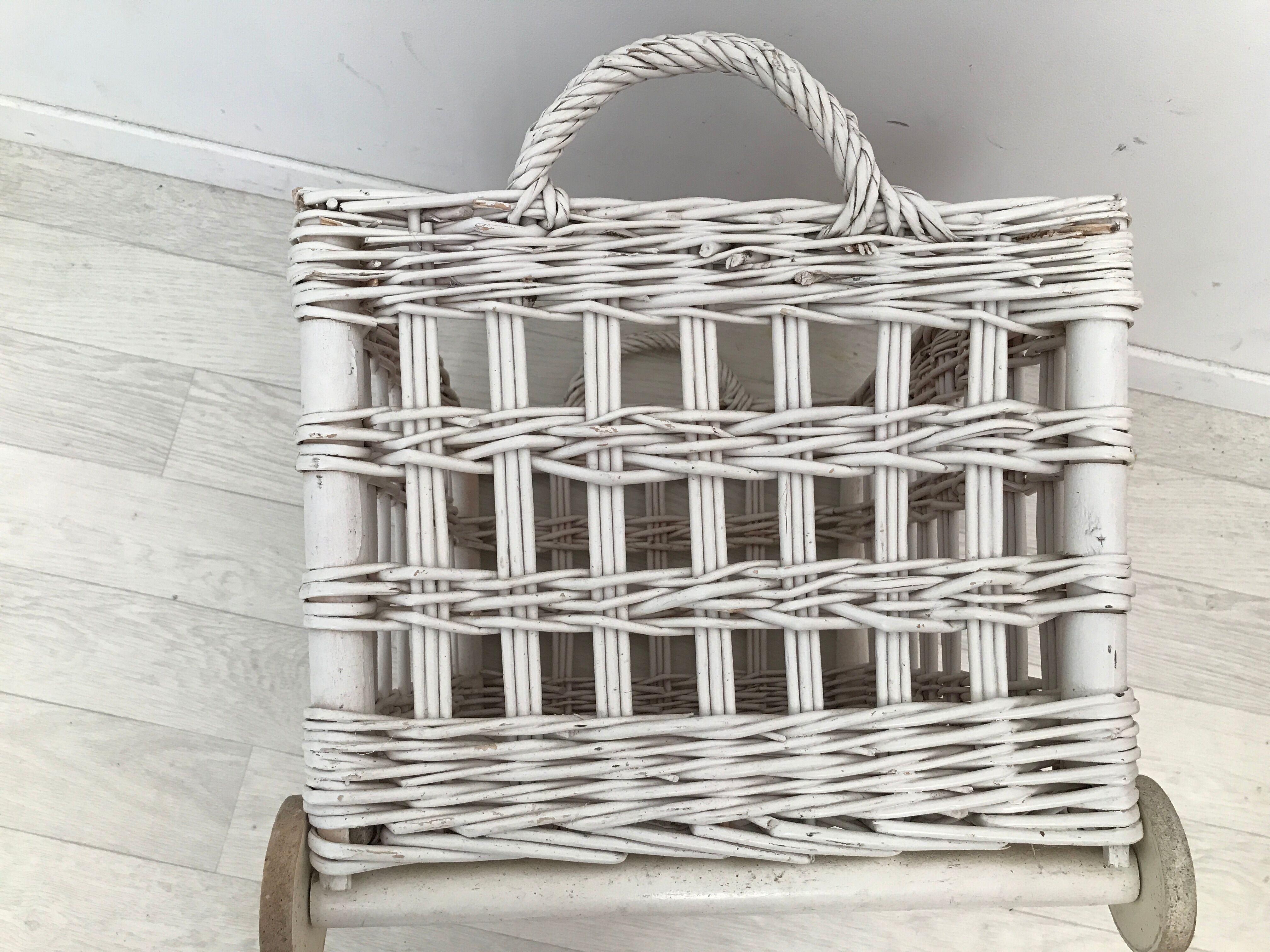 Wicker laundry basket on vintage wooden wheels