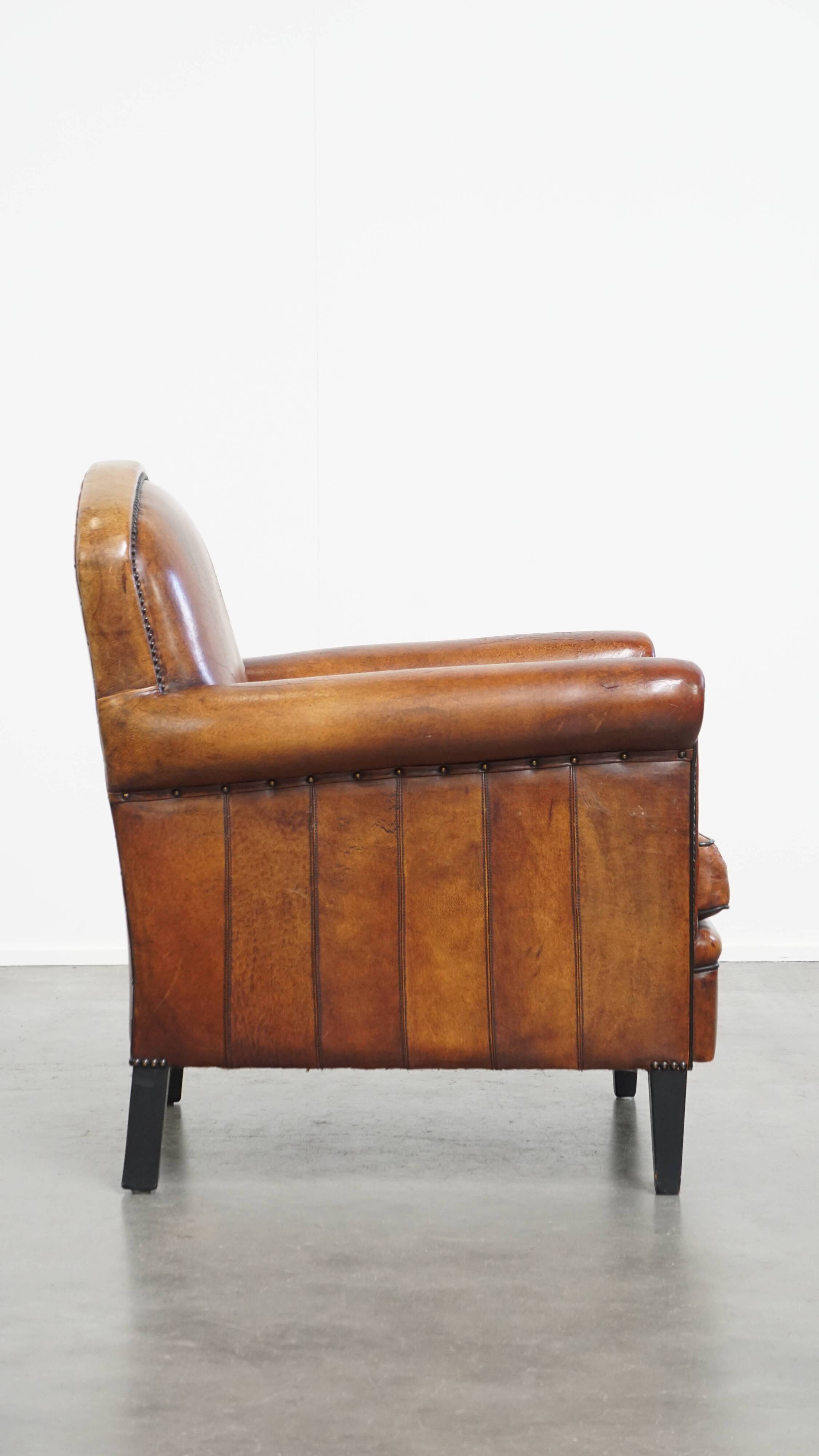 Sheepskin leather armchair in a cognac color with black piping