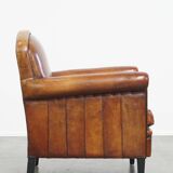 Sheepskin leather armchair in a cognac color with black piping