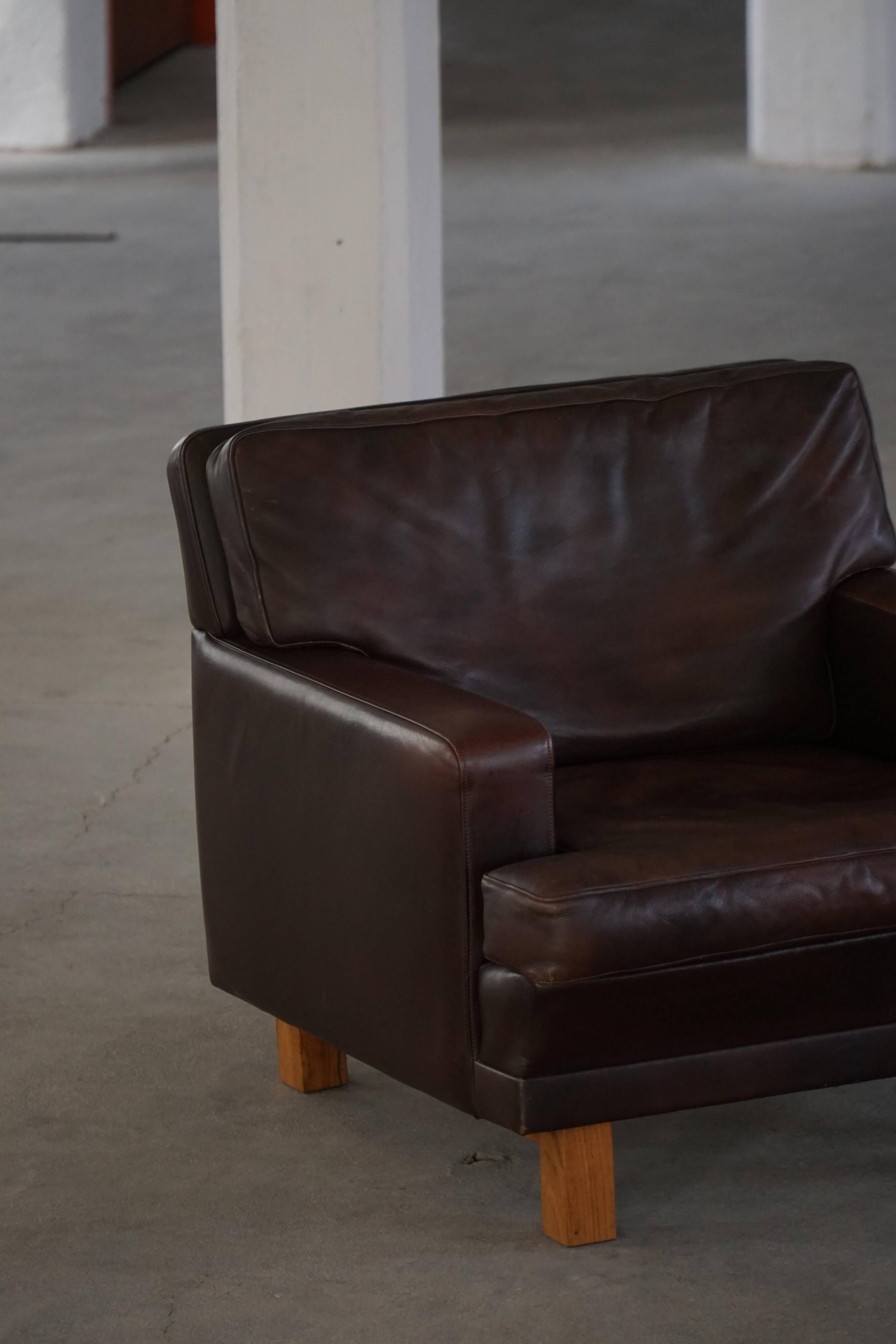 Pair of modern Danish lounge chairs in dark brown leather and rosewood, 1960s.
