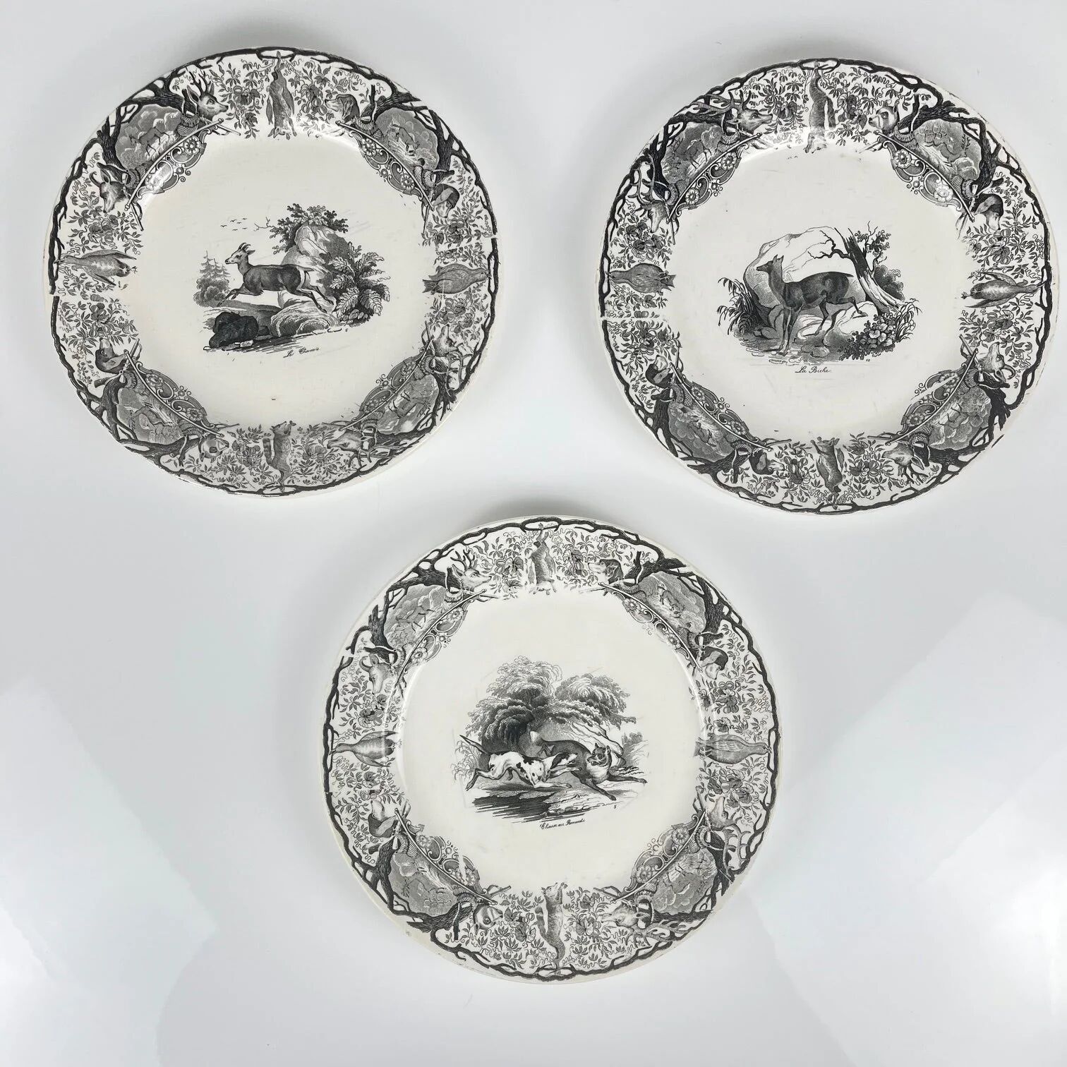 Set of three antique Sarreguemines U&C plates with hunting decoration from 1850 - 19th century black earthenware featuring a doe, chamois, and fox.