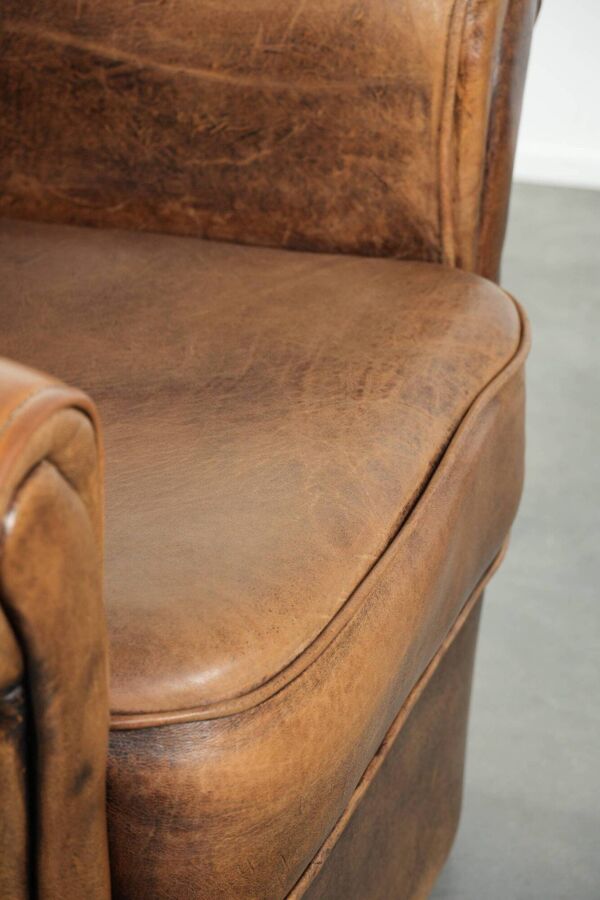 Fauteuil en peau de mouton magnifiquement conçu et confortable, avec un look intemporel et une finition de passepoil assortie.