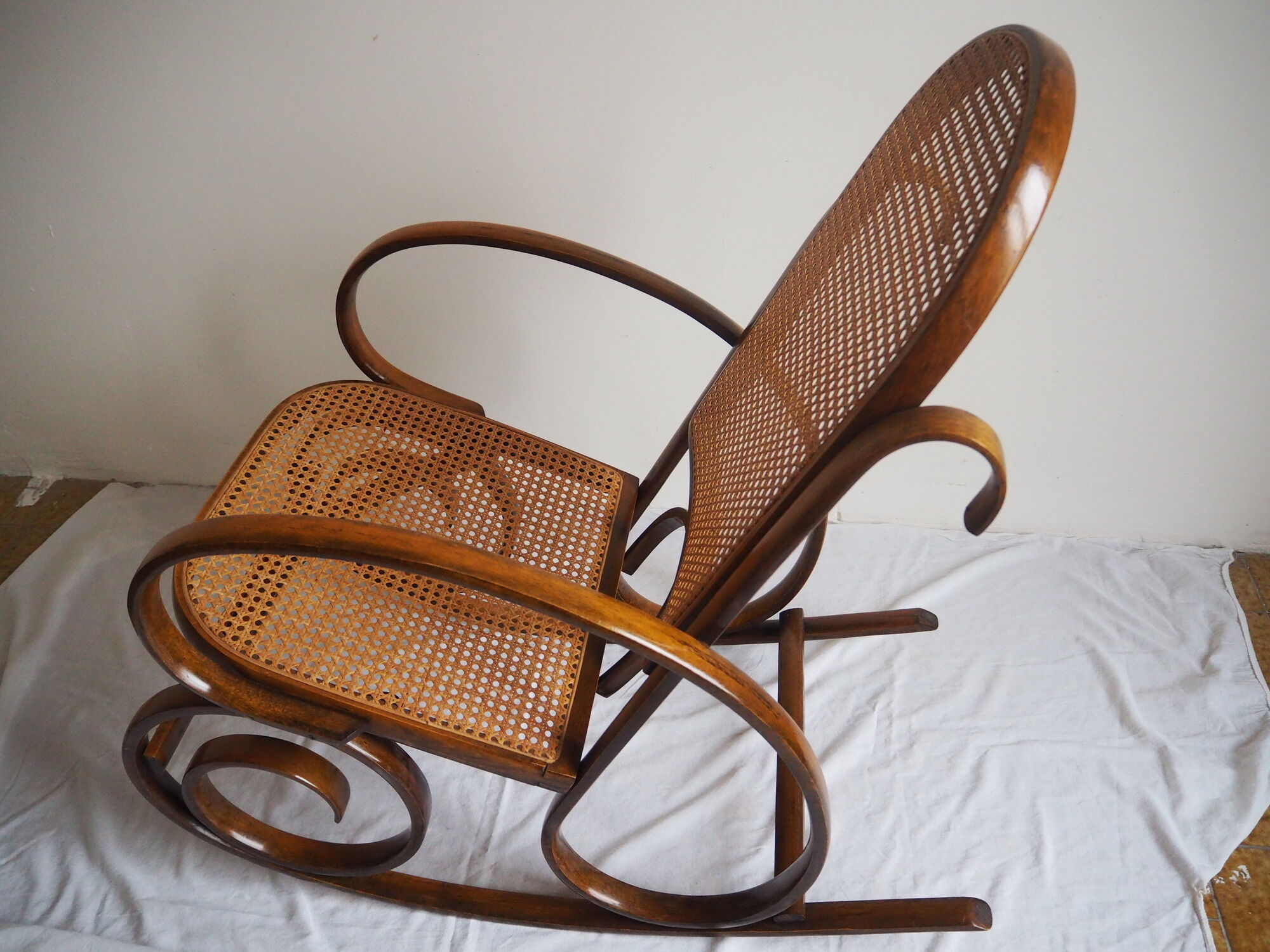 Rocking-chair en bois teinté et assise cannée