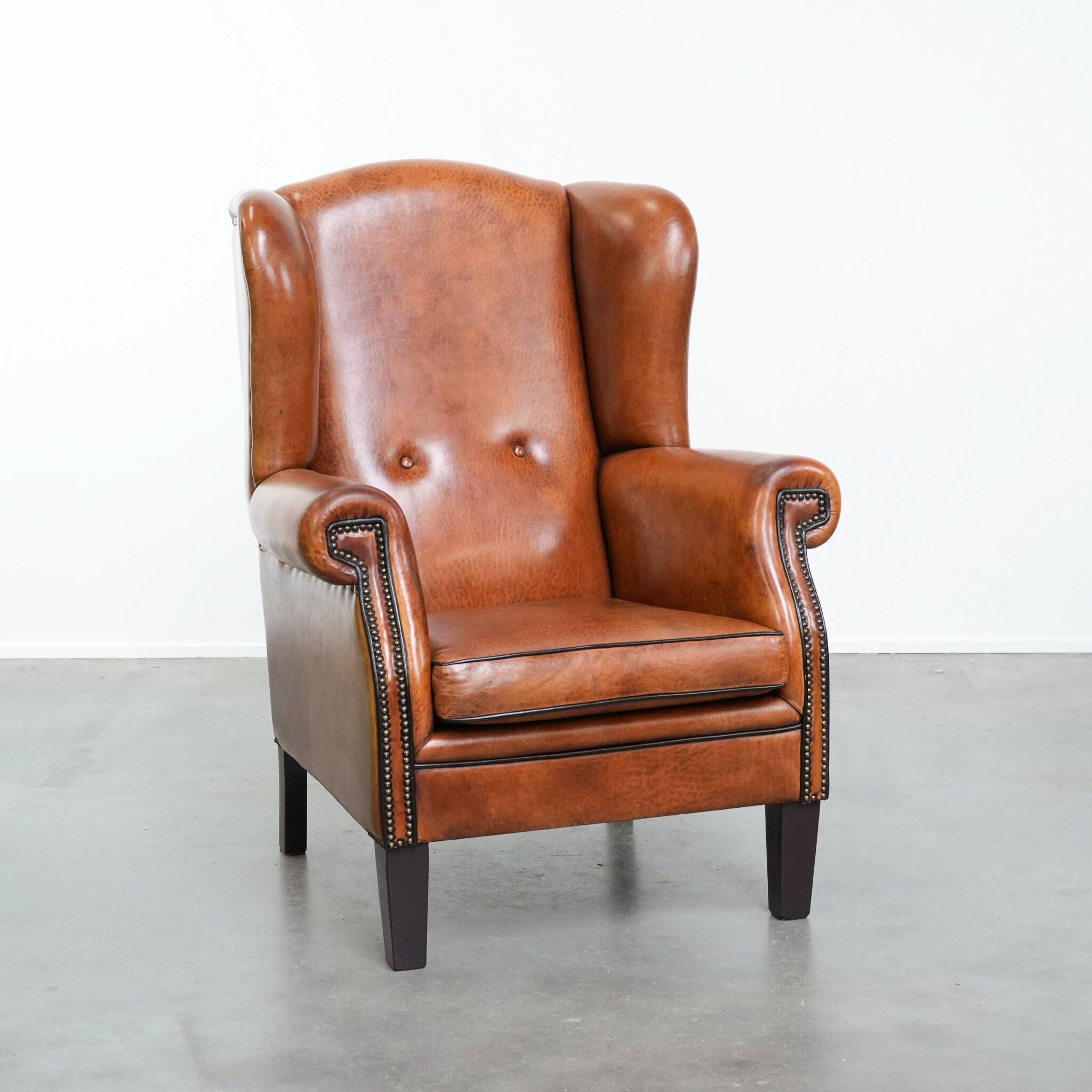 Wingback chair made of sheep leather with black piping in good condition