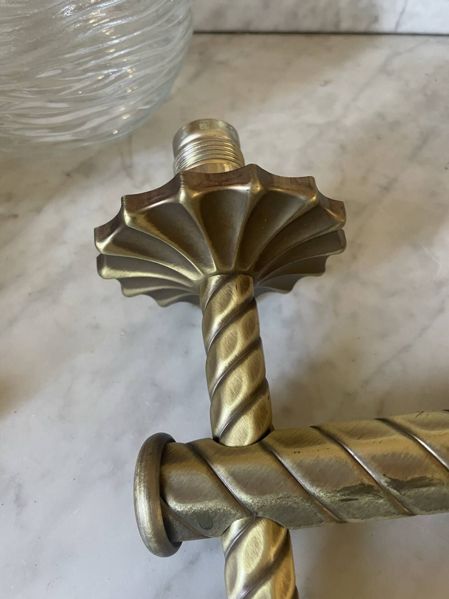 Pair of neoclassical wall sconces in twisted brass and ribbed glass.