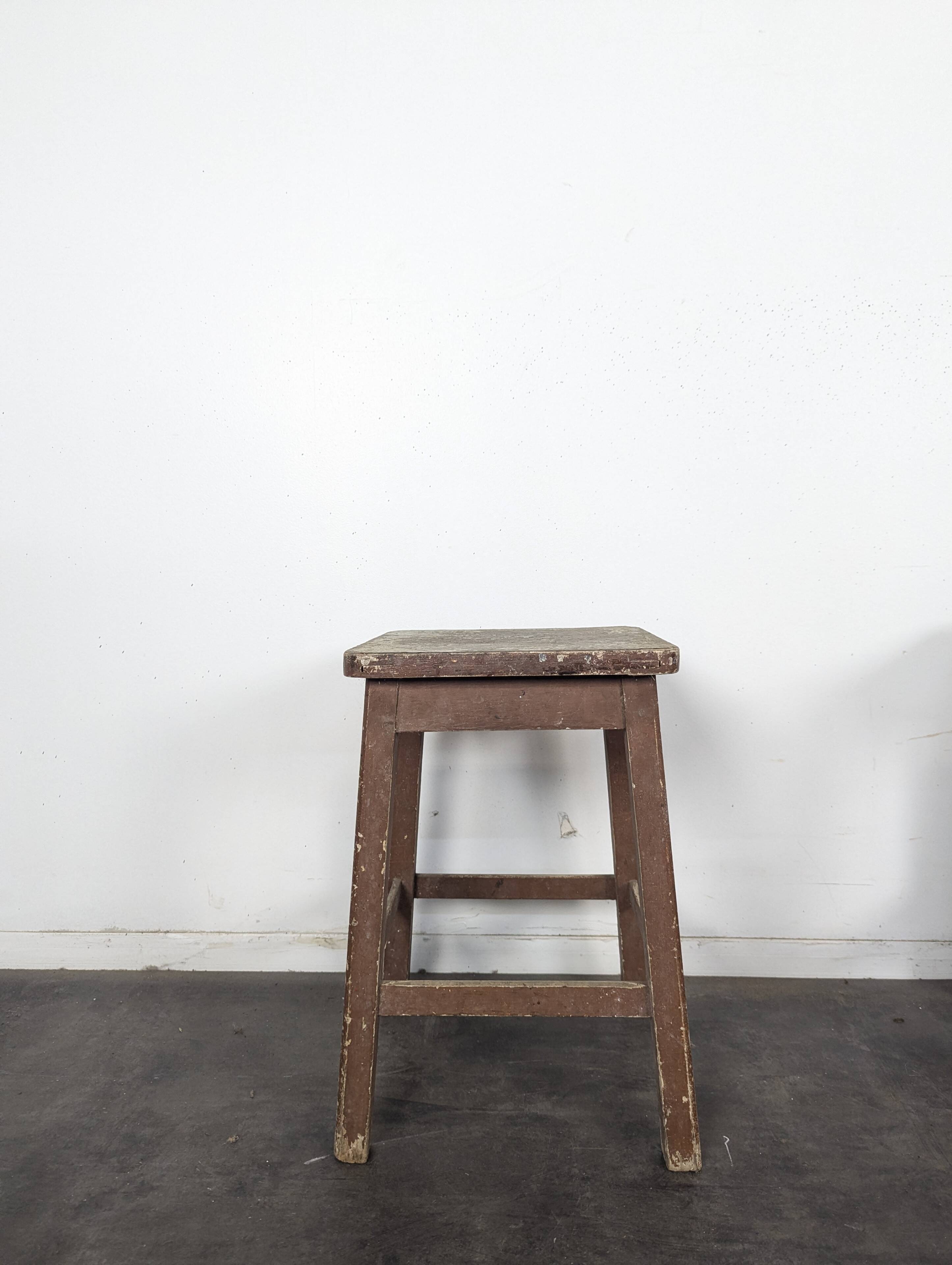 Brown painted wooden workshop stool with a patinated top.