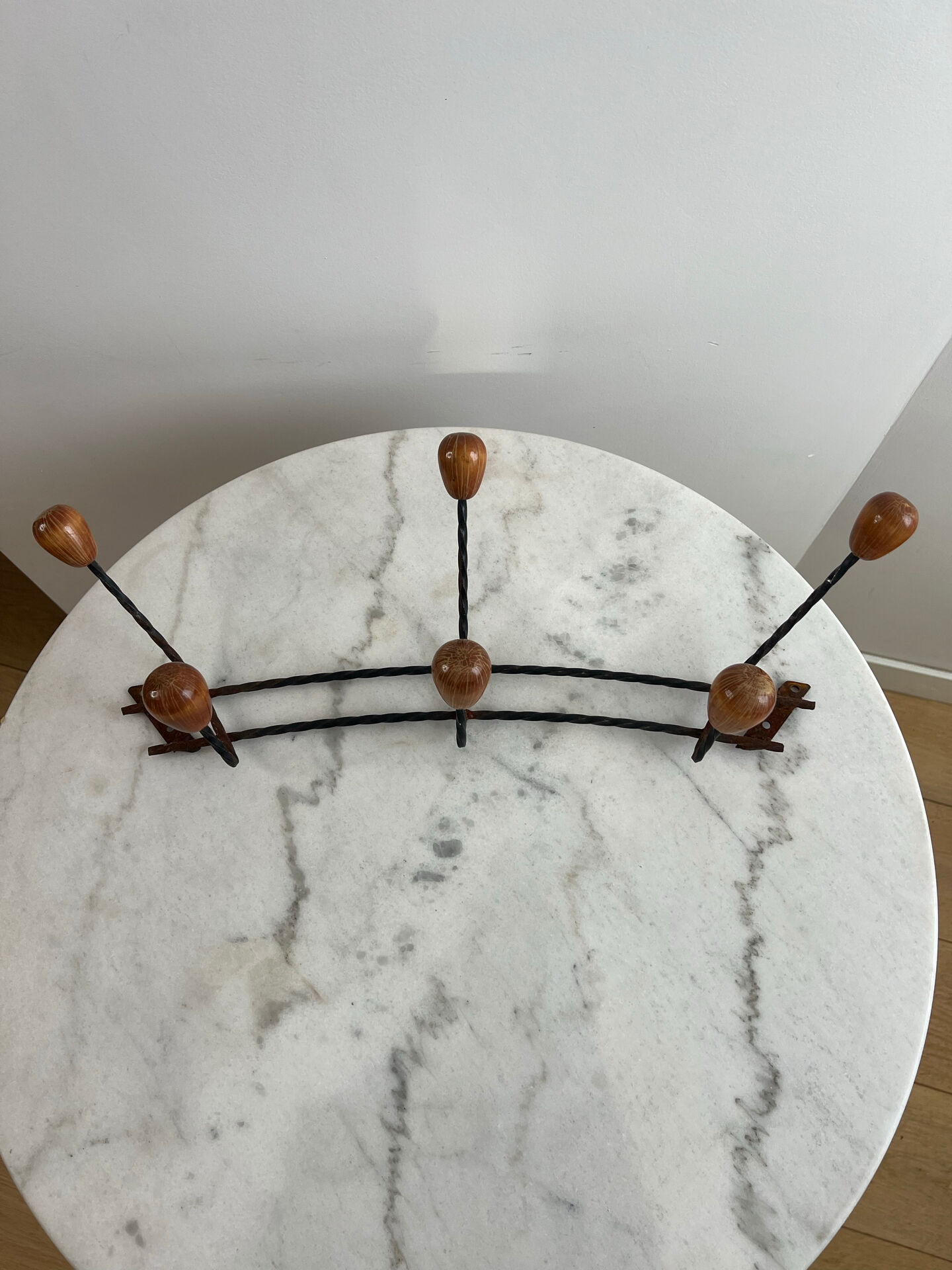 Wall-mounted coat rack in wrought iron with turned wooden knobs.