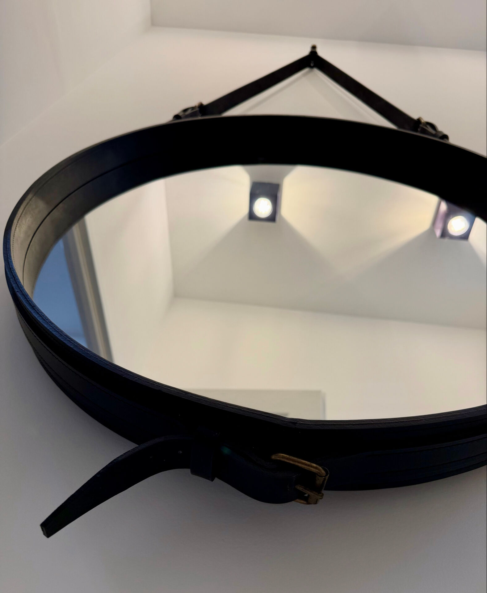 Round mirror covered in black leather in the style of Jacques Adnet.