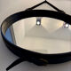 Round mirror covered in black leather in the style of Jacques Adnet.