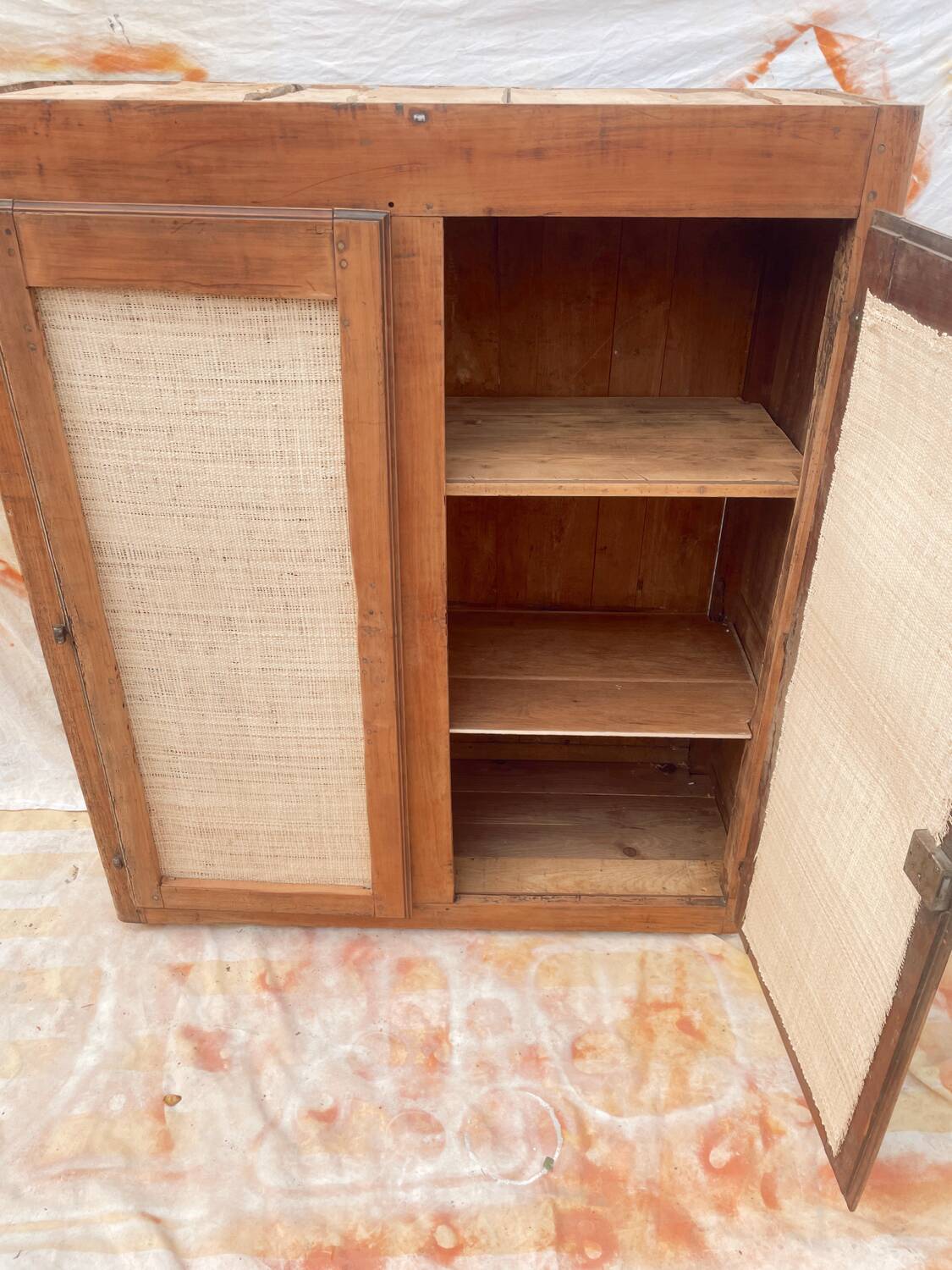 Low cabinet in raw wood and woven raffia.