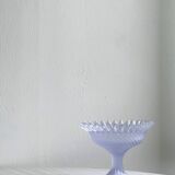 Purple glass pedestal bowl with wavy border and relief pattern.