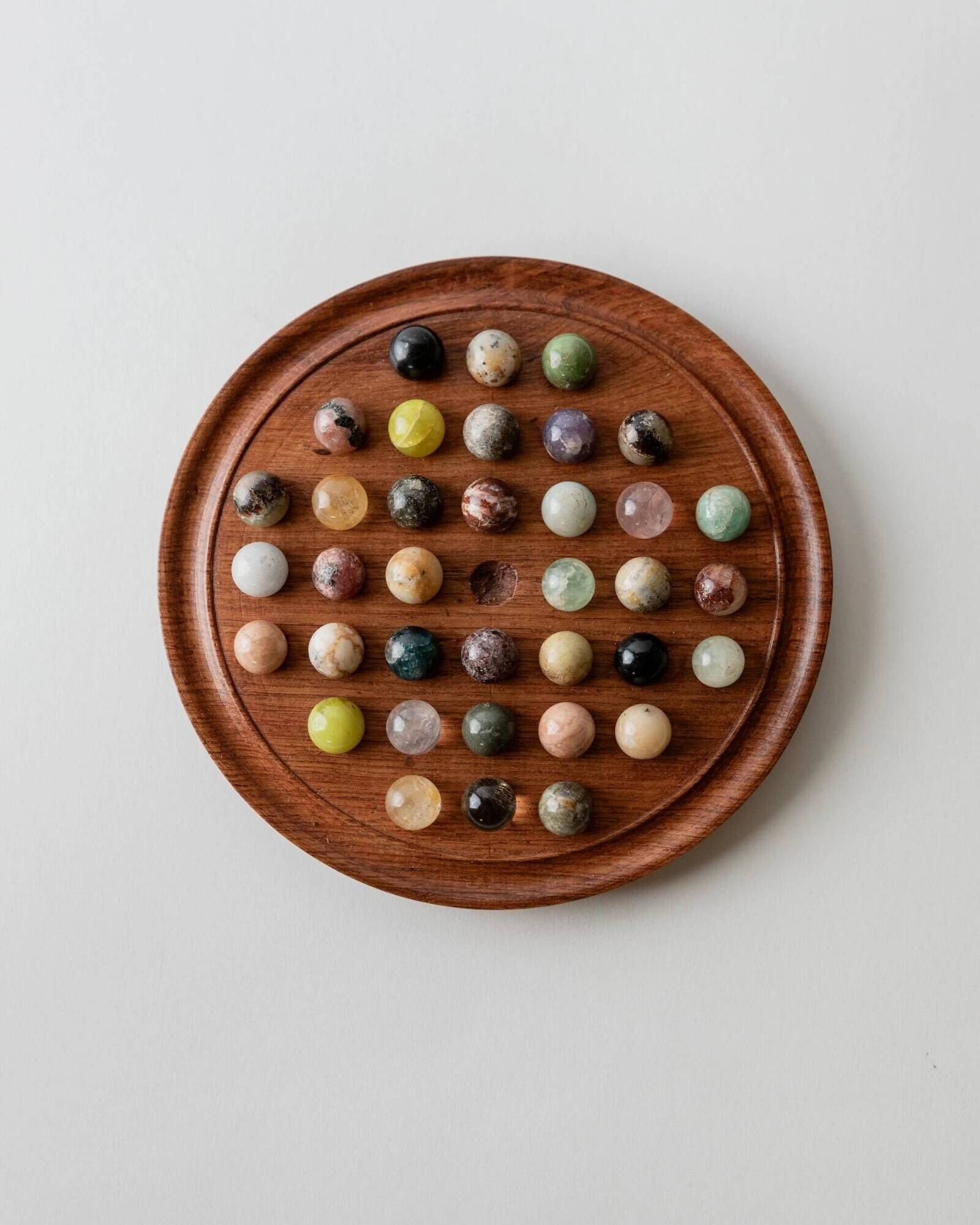 Vintage 1960s solitaire game, wooden board with stone marbles.