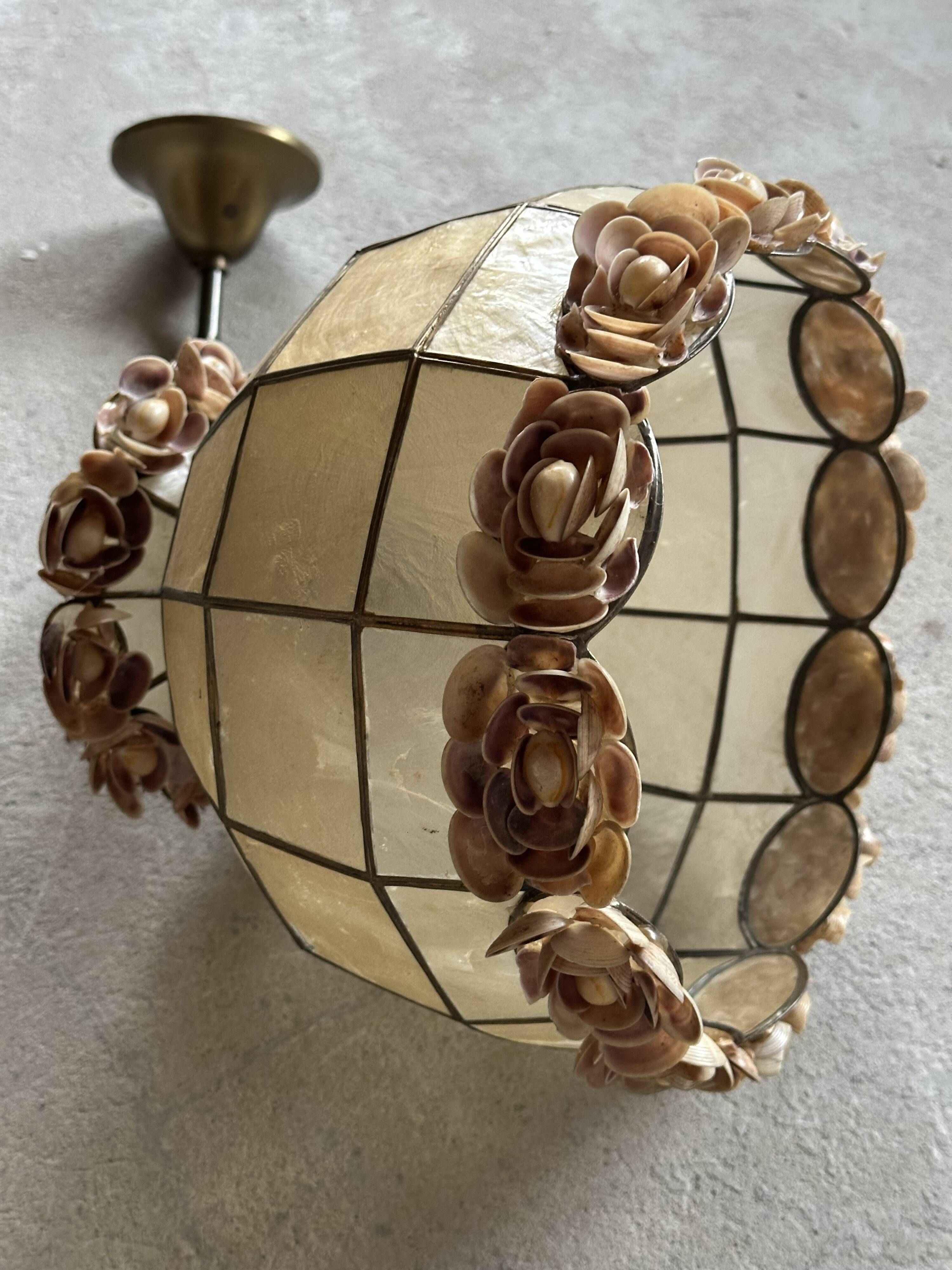 Vintage pendant light with a pearlescent shade and floral decoration.