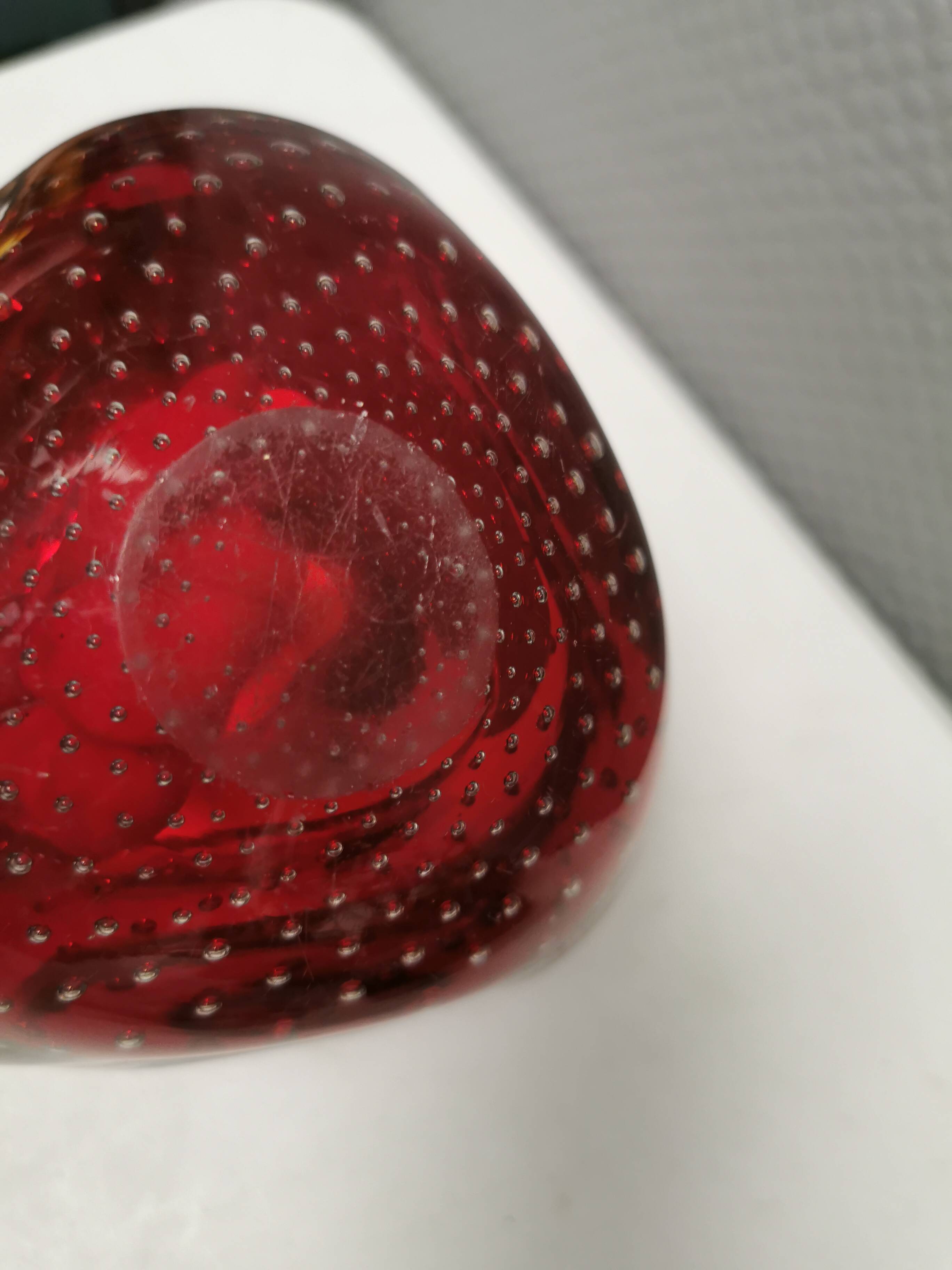 Small glass bowl in beautiful emerald red color with inlaid bubbles.