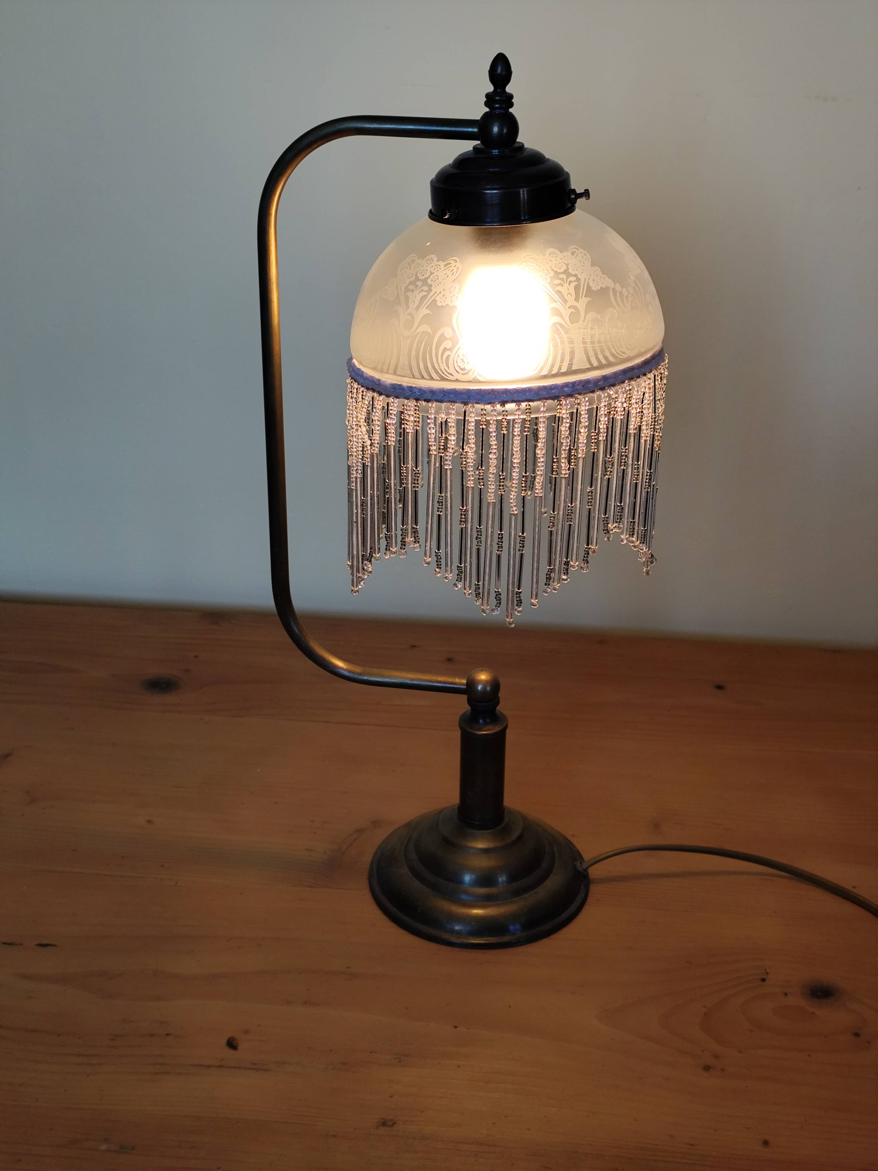 Retro brass lamp with a glass shade and bead fringes.