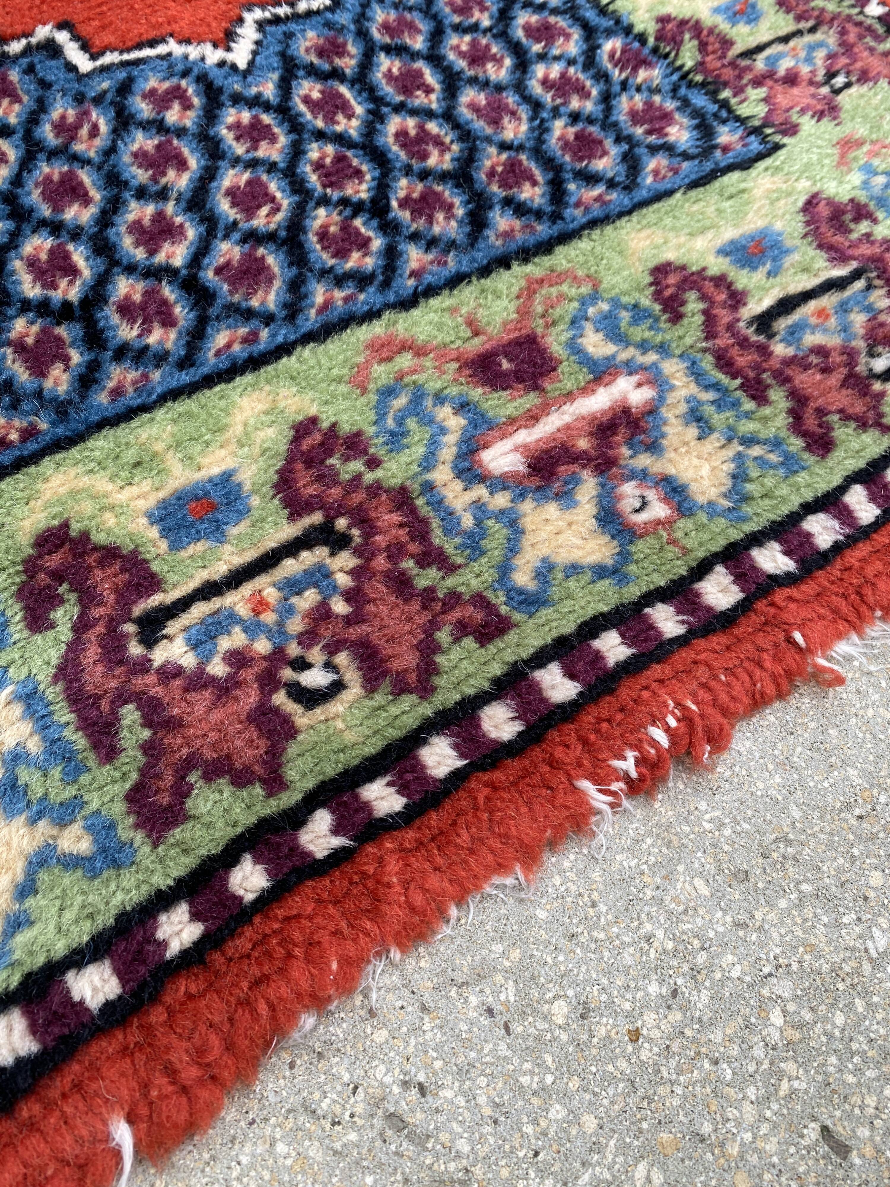 Vintage hand-knotted wool rug with polychrome decoration on a red, blue, green background 150 x 63 cm