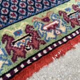 Vintage hand-knotted wool rug with polychrome decoration on a red, blue, green background 150 x 63 cm