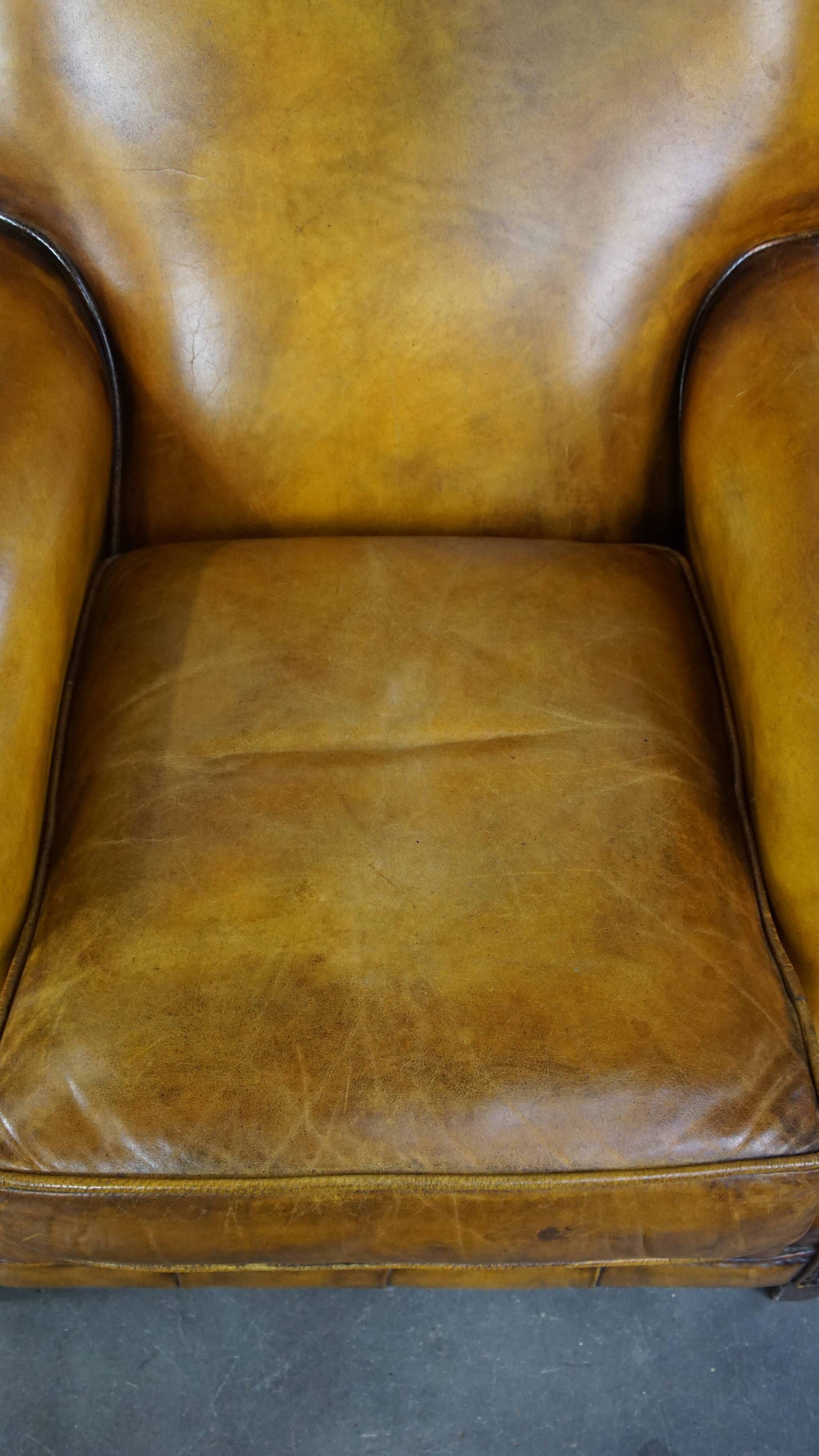 Comfortable large yellow English-style leather armchair with a fine finish and decorative nails