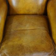 Comfortable large yellow English-style leather armchair with a fine finish and decorative nails