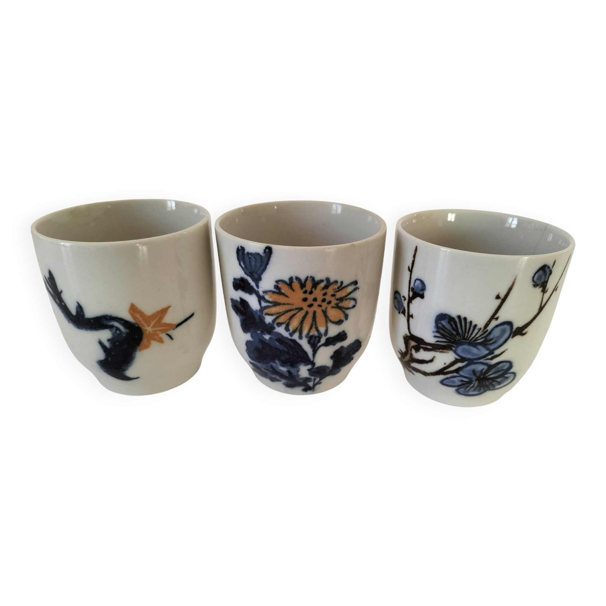 Set of three hand-painted porcelain cups with floral patterns.