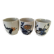 Set of three hand-painted porcelain cups with floral patterns.