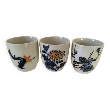 Set of three hand-painted porcelain cups with floral patterns.