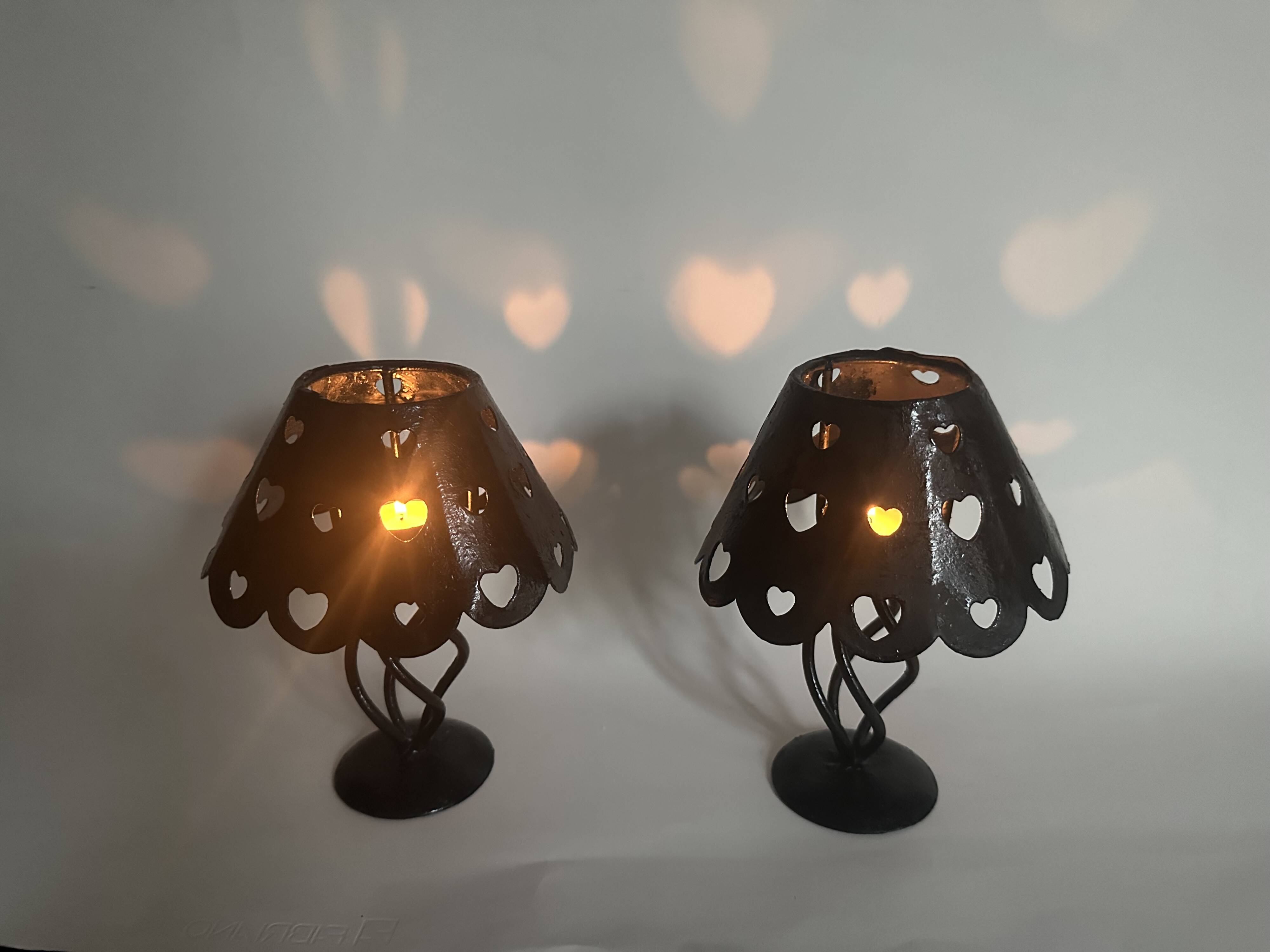 Pair of black wrought iron lanterns with heart patterns, romantic style.